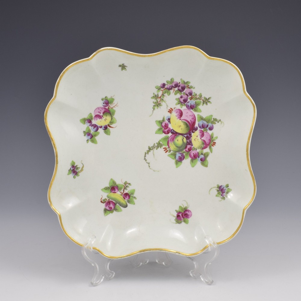 An eighteenth-century square lobed soft-paste porcelain dessert dish featuring hand-painted fruit sprays and a gilded rim.