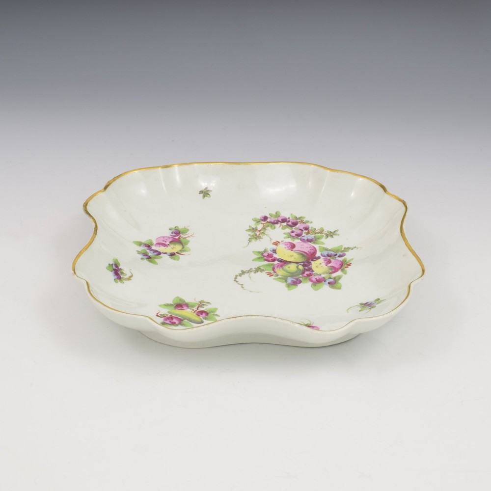 An eighteenth-century square lobed soft-paste porcelain dessert dish featuring hand-painted fruit sprays and a gilded rim. View VI