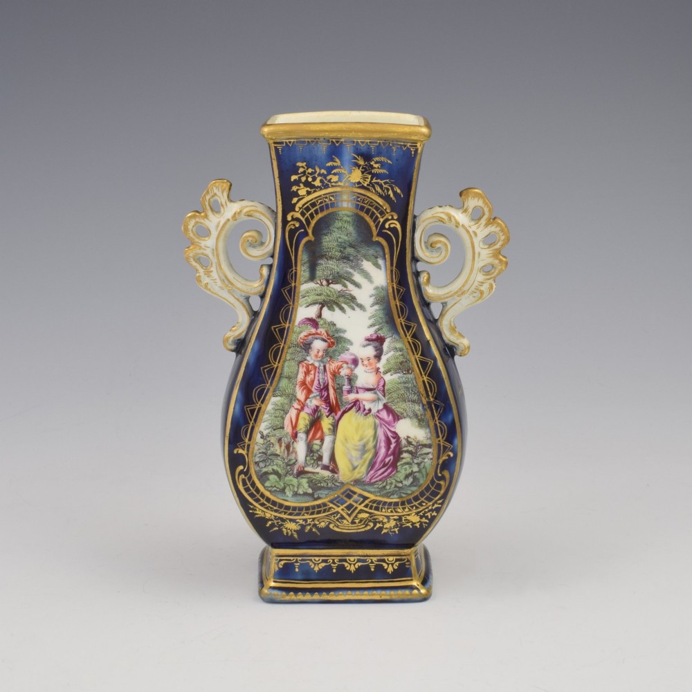 A cobalt blue soft-paste porcelain vase featuring elaborate gilt scroll handles, gilded leaf borders, and a central painted reserve depicting a gentleman playing a lute beside a lady in a landscape. View VIII