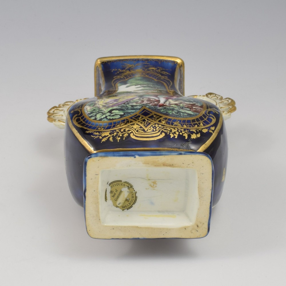 A cobalt blue soft-paste porcelain vase featuring elaborate gilt scroll handles, gilded leaf borders, and a central painted reserve depicting a gentleman playing a lute beside a lady in a landscape. View XII