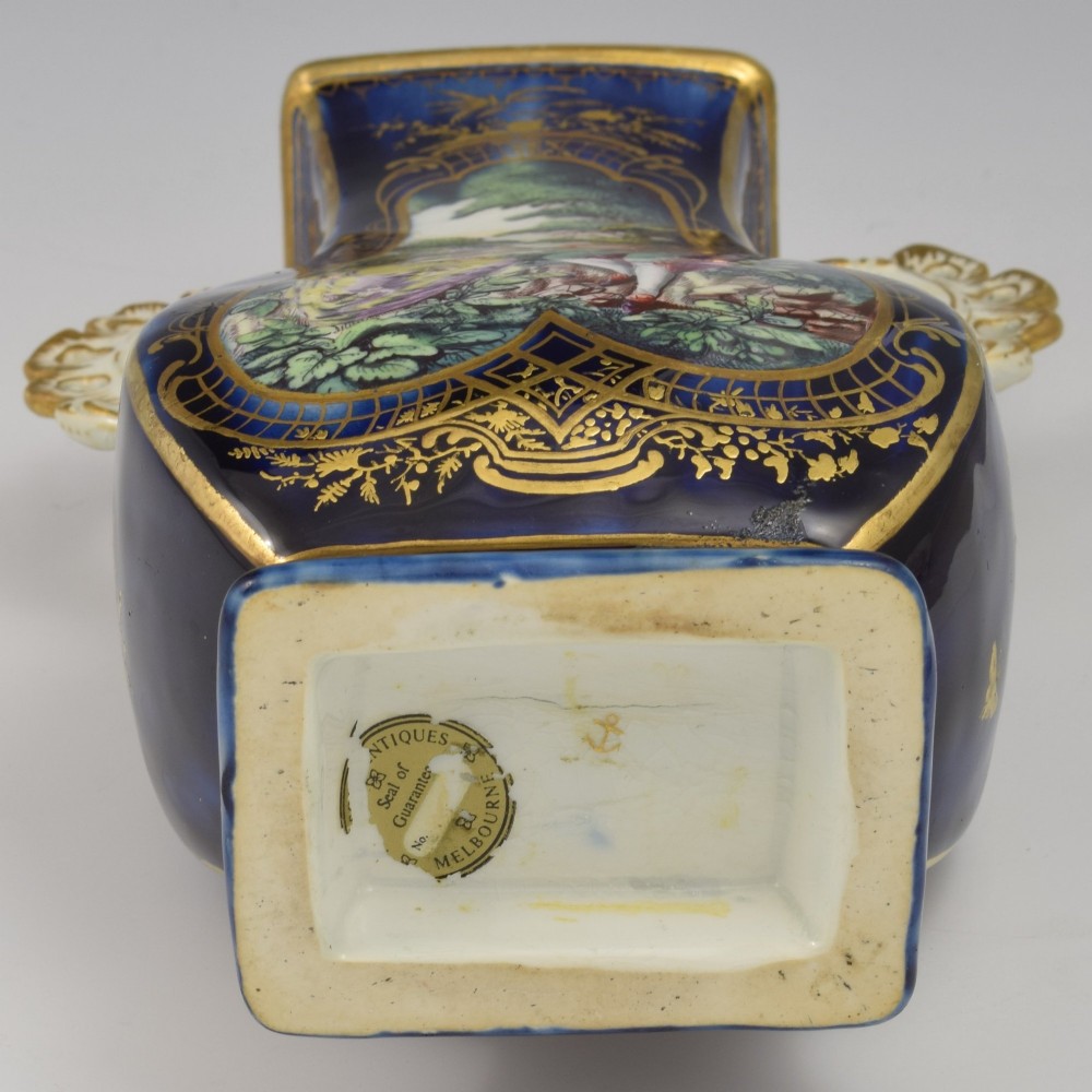 A cobalt blue soft-paste porcelain vase featuring elaborate gilt scroll handles, gilded leaf borders, and a central painted reserve depicting a gentleman playing a lute beside a lady in a landscape. View XIII
