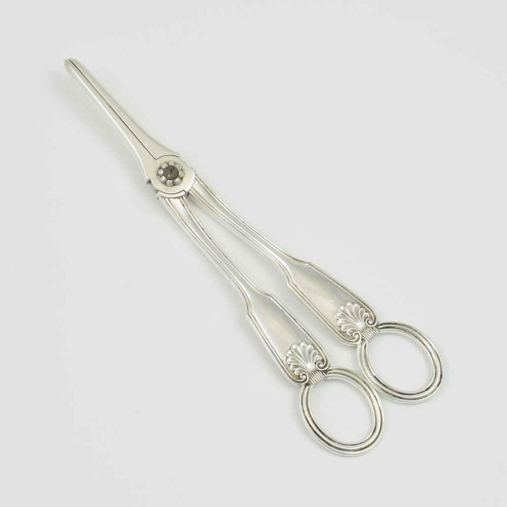 A pair of late Victorian sterling silver grape scissors featuring shell motifs near the oval finger loops and molded handles.