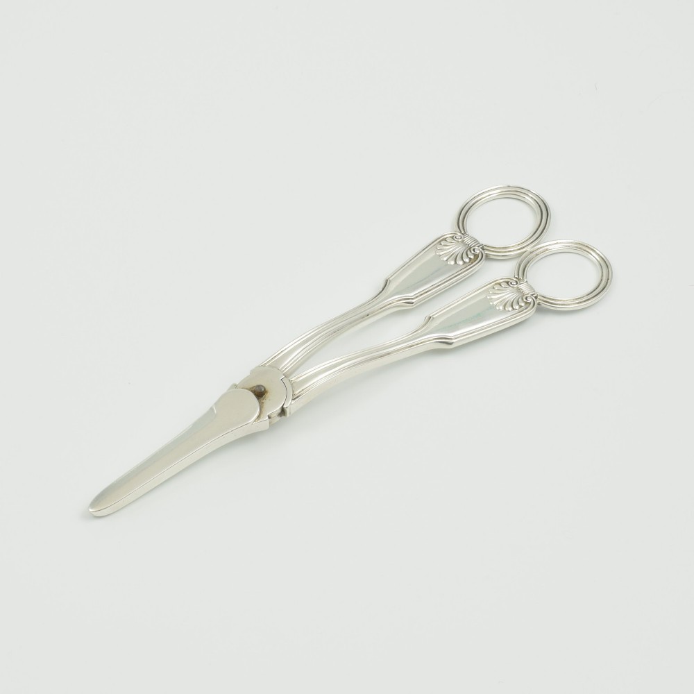 A pair of late Victorian sterling silver grape scissors featuring shell motifs near the oval finger loops and molded handles. View VII