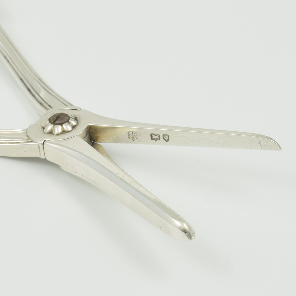 A pair of late Victorian sterling silver grape scissors featuring shell motifs near the oval finger loops and molded handles. View IX