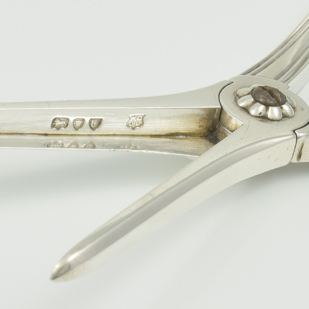 A pair of late Victorian sterling silver grape scissors featuring shell motifs near the oval finger loops and molded handles. View X