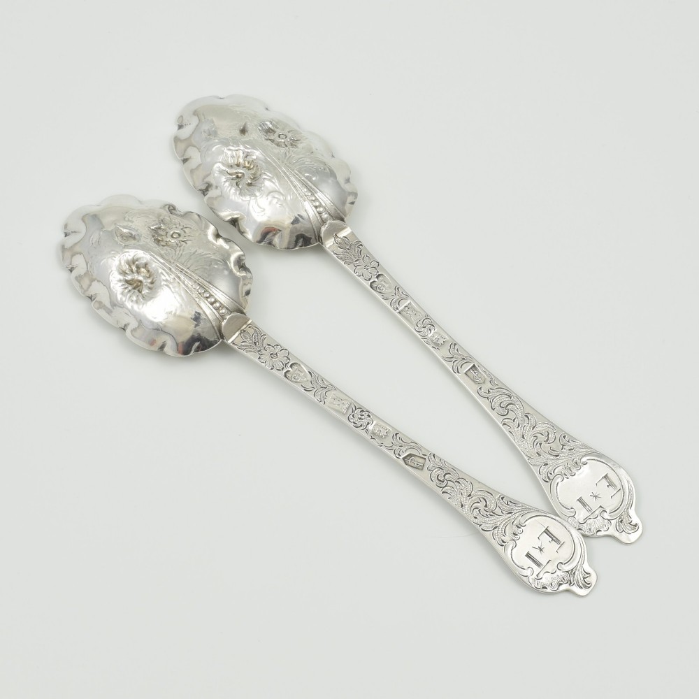 A pair of William III sterling silver dognose spoons featuring chased floral stems and gilded, scalloped bowls. View III