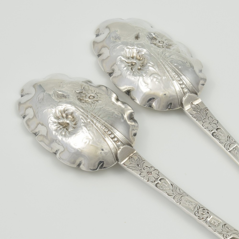 A pair of William III sterling silver dognose spoons featuring chased floral stems and gilded, scalloped bowls. View IV