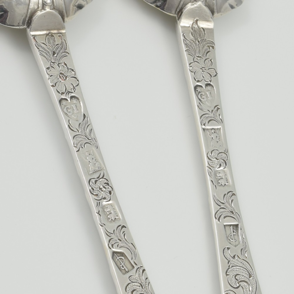 A pair of William III sterling silver dognose spoons featuring chased floral stems and gilded, scalloped bowls. View V