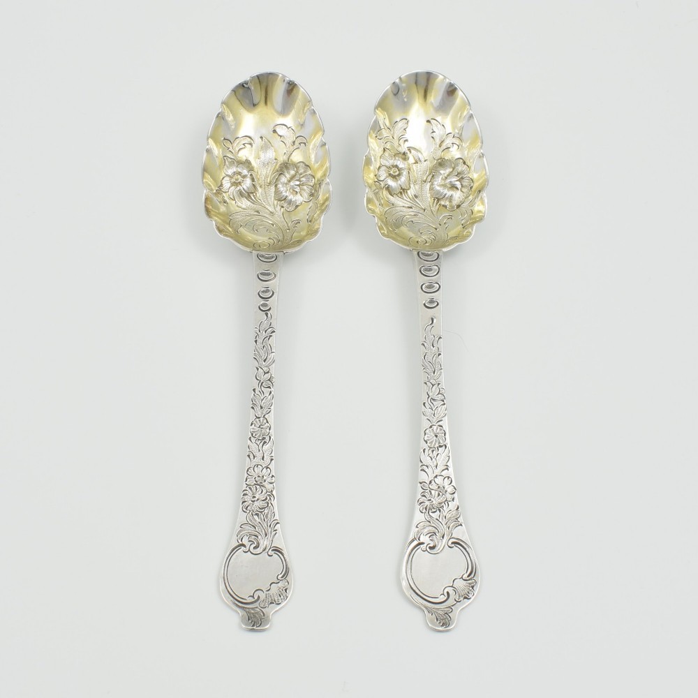 A pair of William III sterling silver dognose spoons featuring chased floral stems and gilded, scalloped bowls. View IX