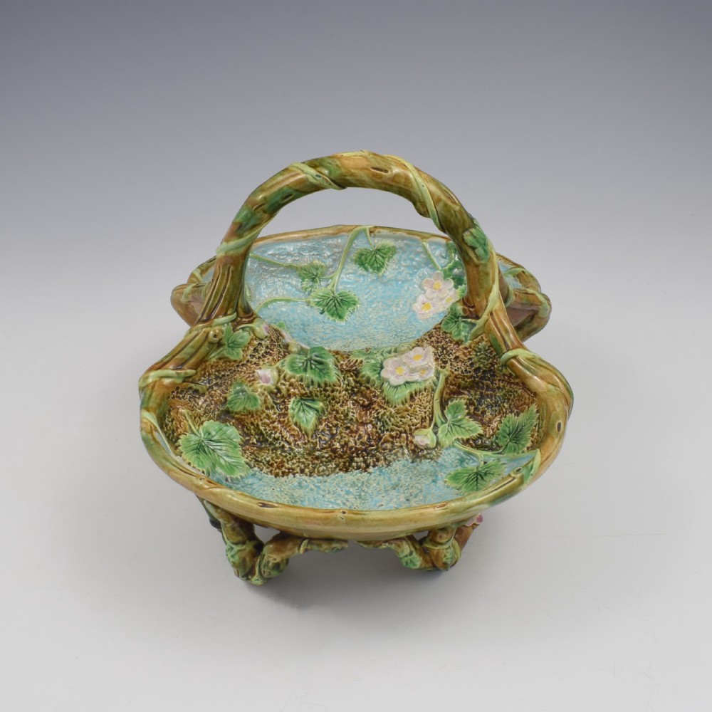 A Victorian George Jones majolica strawberry basket featuring double compartments decorated with relief leaves, pink blossoms, and an overarching branch handle in green, brown, and turquoise glazes. View IV