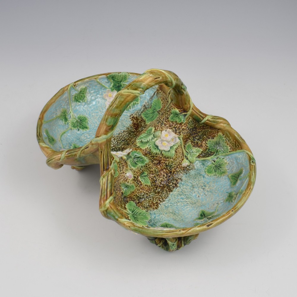 A Victorian George Jones majolica strawberry basket featuring double compartments decorated with relief leaves, pink blossoms, and an overarching branch handle in green, brown, and turquoise glazes. View V