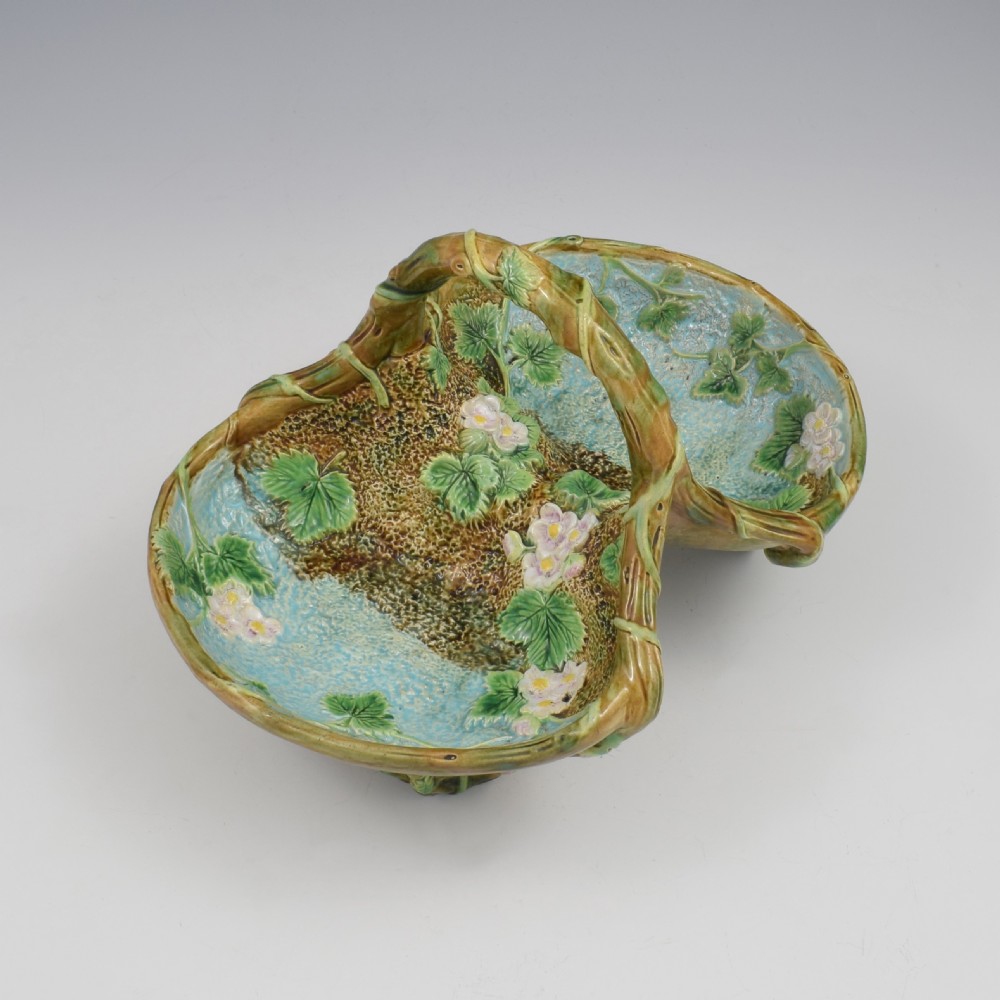 A Victorian George Jones majolica strawberry basket featuring double compartments decorated with relief leaves, pink blossoms, and an overarching branch handle in green, brown, and turquoise glazes. View VII