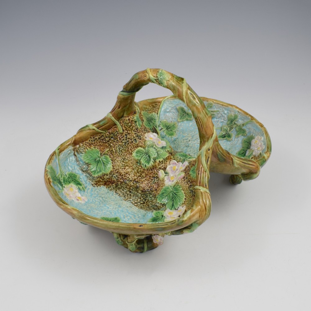 A Victorian George Jones majolica strawberry basket featuring double compartments decorated with relief leaves, pink blossoms, and an overarching branch handle in green, brown, and turquoise glazes. View VIII