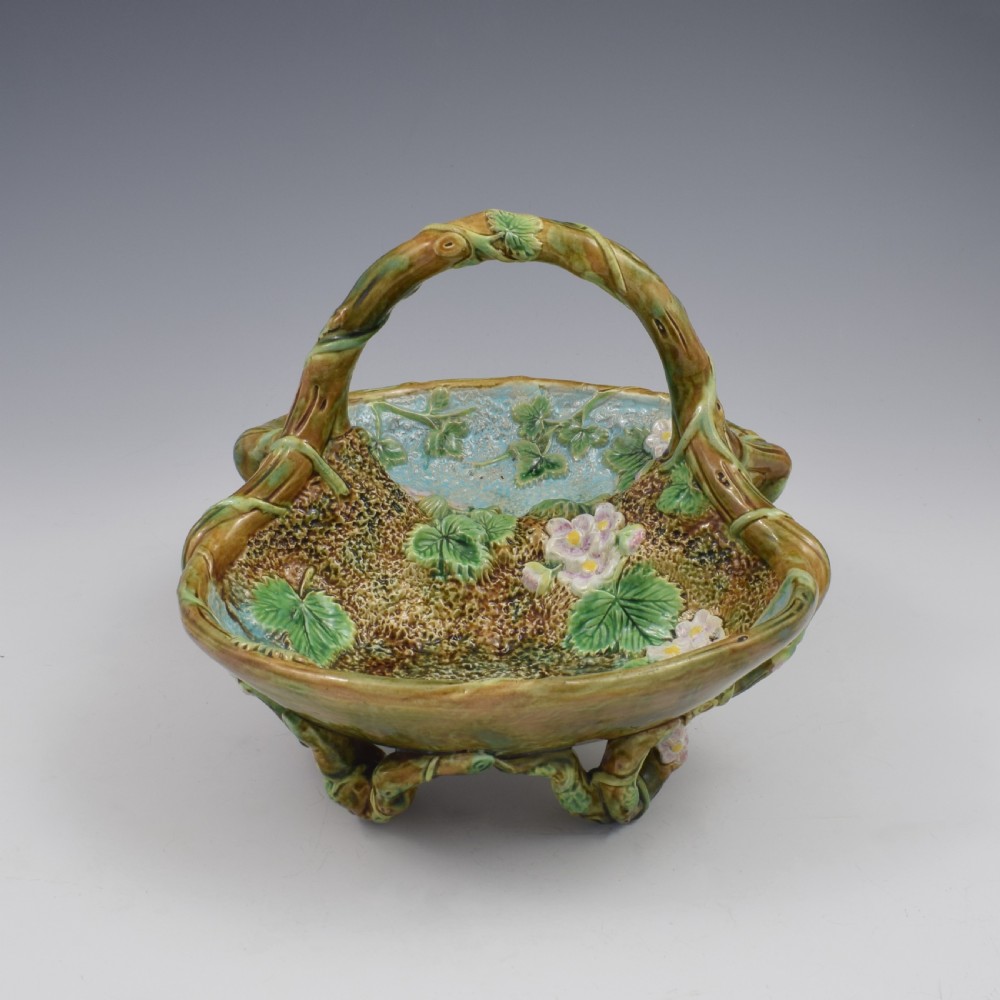 A Victorian George Jones majolica strawberry basket featuring double compartments decorated with relief leaves, pink blossoms, and an overarching branch handle in green, brown, and turquoise glazes. View X