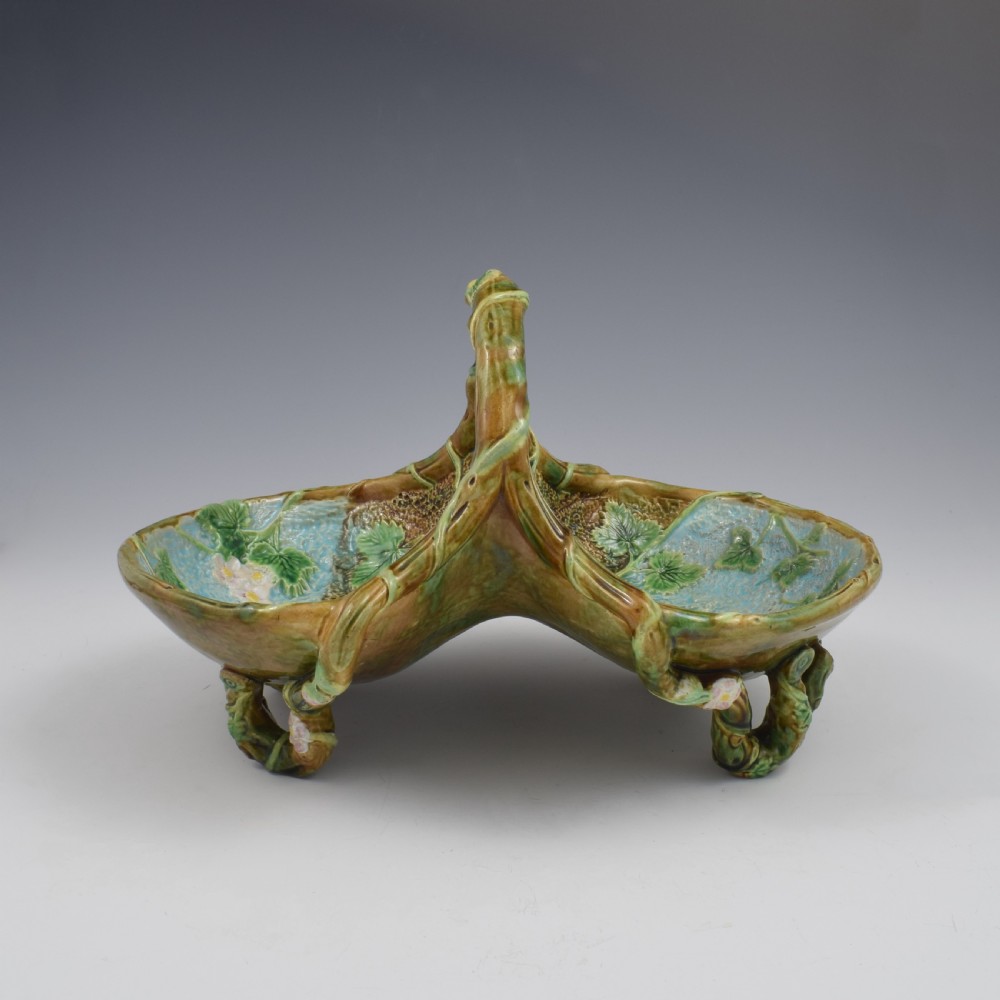 A Victorian George Jones majolica strawberry basket featuring double compartments decorated with relief leaves, pink blossoms, and an overarching branch handle in green, brown, and turquoise glazes. View XI