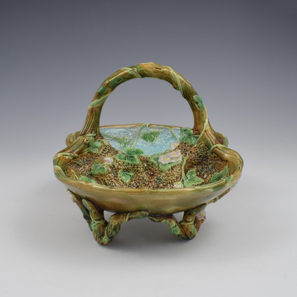 A Victorian George Jones majolica strawberry basket featuring double compartments decorated with relief leaves, pink blossoms, and an overarching branch handle in green, brown, and turquoise glazes. View XII