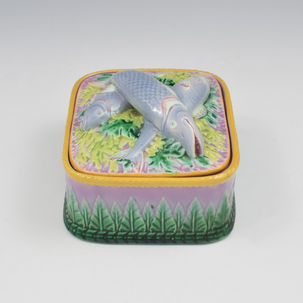 A rectangular Victorian majolica lidded box in lilac and pink featuring relief-moulded fish resting on seaweed with a yellow rim and green leaf base. View III