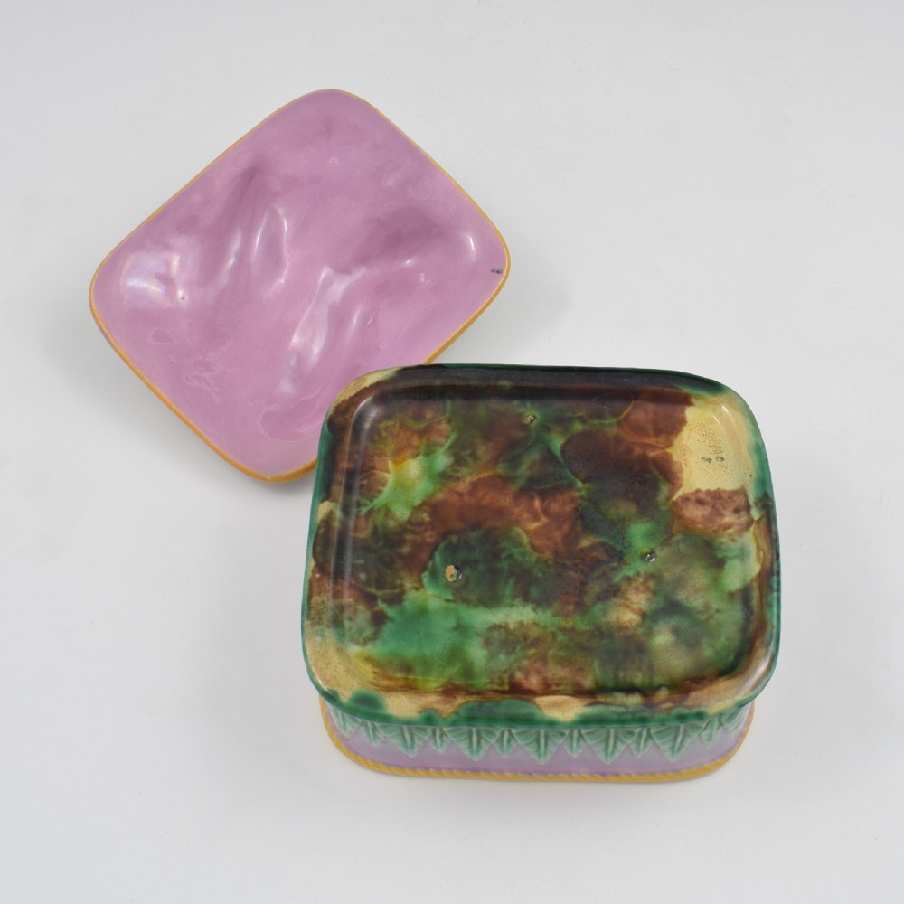 A rectangular Victorian majolica lidded box in lilac and pink featuring relief-moulded fish resting on seaweed with a yellow rim and green leaf base. View VII