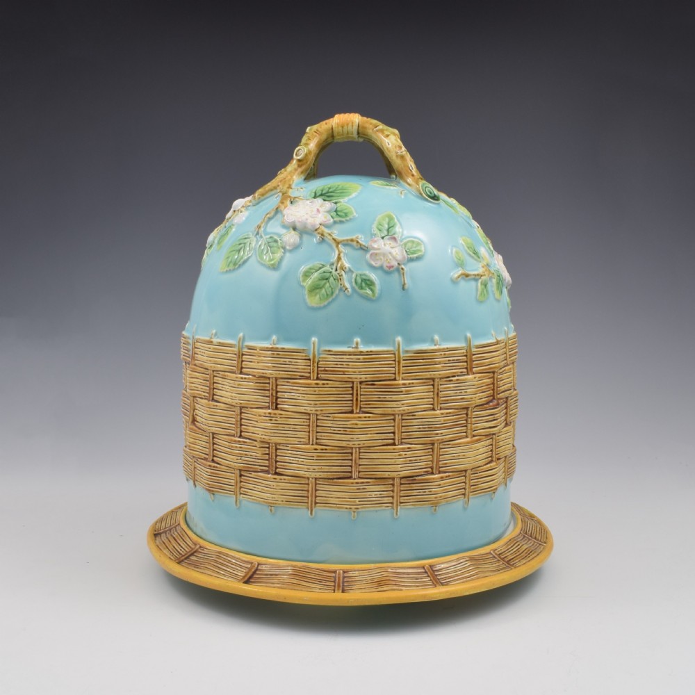 A Victorian George Jones majolica cheese bell and stand featuring a turquoise dome decorated with relief apple blossoms, a woven basketweave lower band, and a twig-form handle. View II