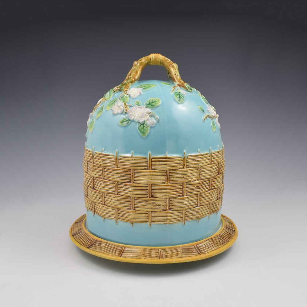 A Victorian George Jones majolica cheese bell and stand featuring a turquoise dome decorated with relief apple blossoms, a woven basketweave lower band, and a twig-form handle. View V
