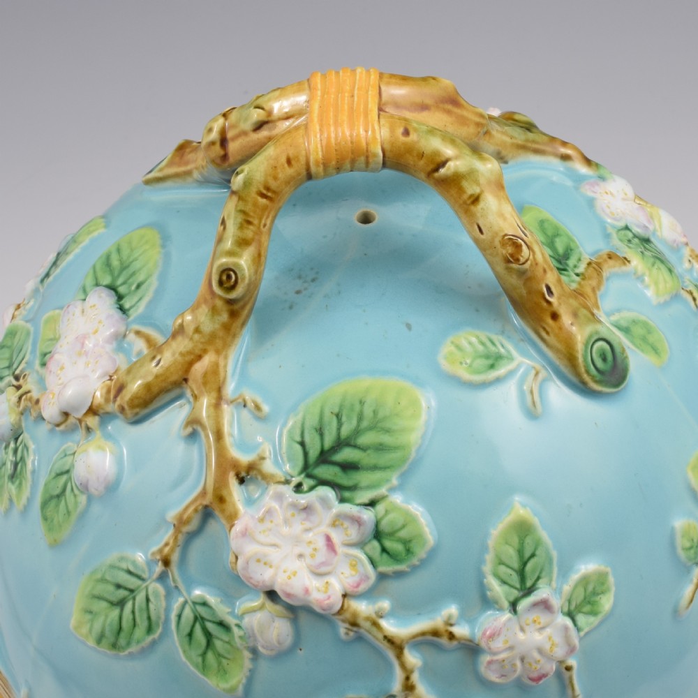 A Victorian George Jones majolica cheese bell and stand featuring a turquoise dome decorated with relief apple blossoms, a woven basketweave lower band, and a twig-form handle. View VII