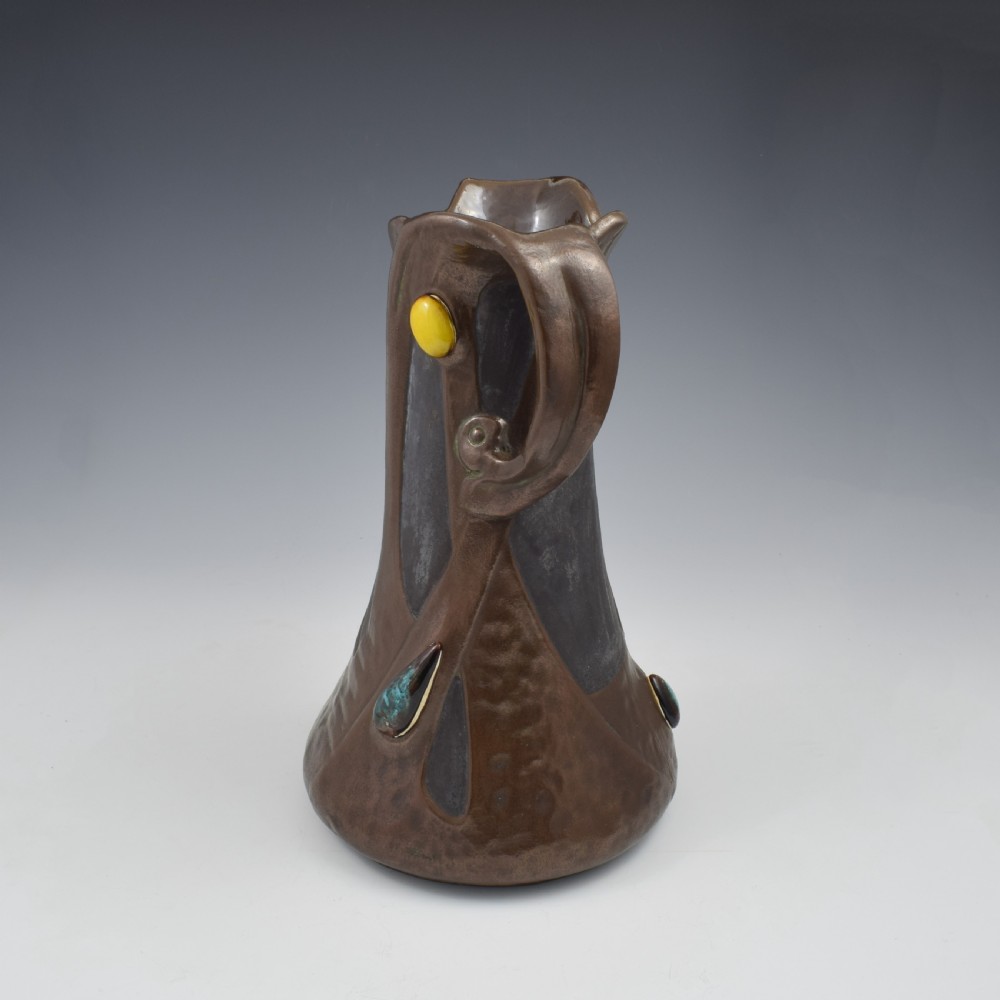 An Art Nouveau brown ceramic vase featuring a metallic copper effect surface, organic twin handles, flared rim, and inset colourful glazed cabochons. View III
