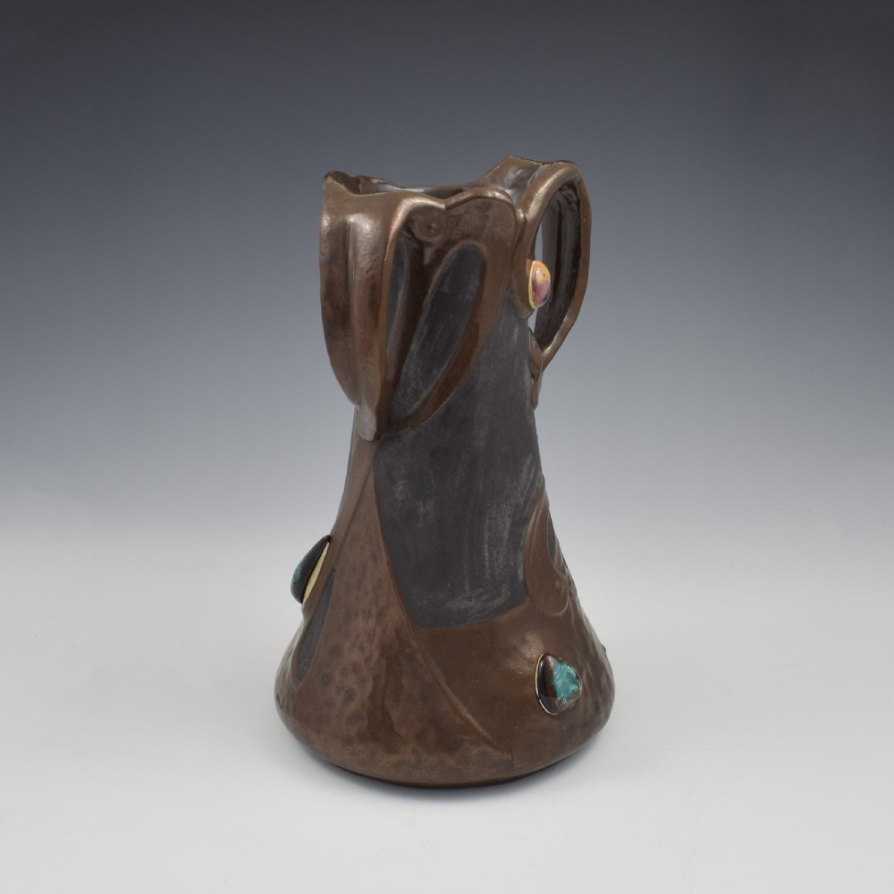 An Art Nouveau brown ceramic vase featuring a metallic copper effect surface, organic twin handles, flared rim, and inset colourful glazed cabochons. View IV