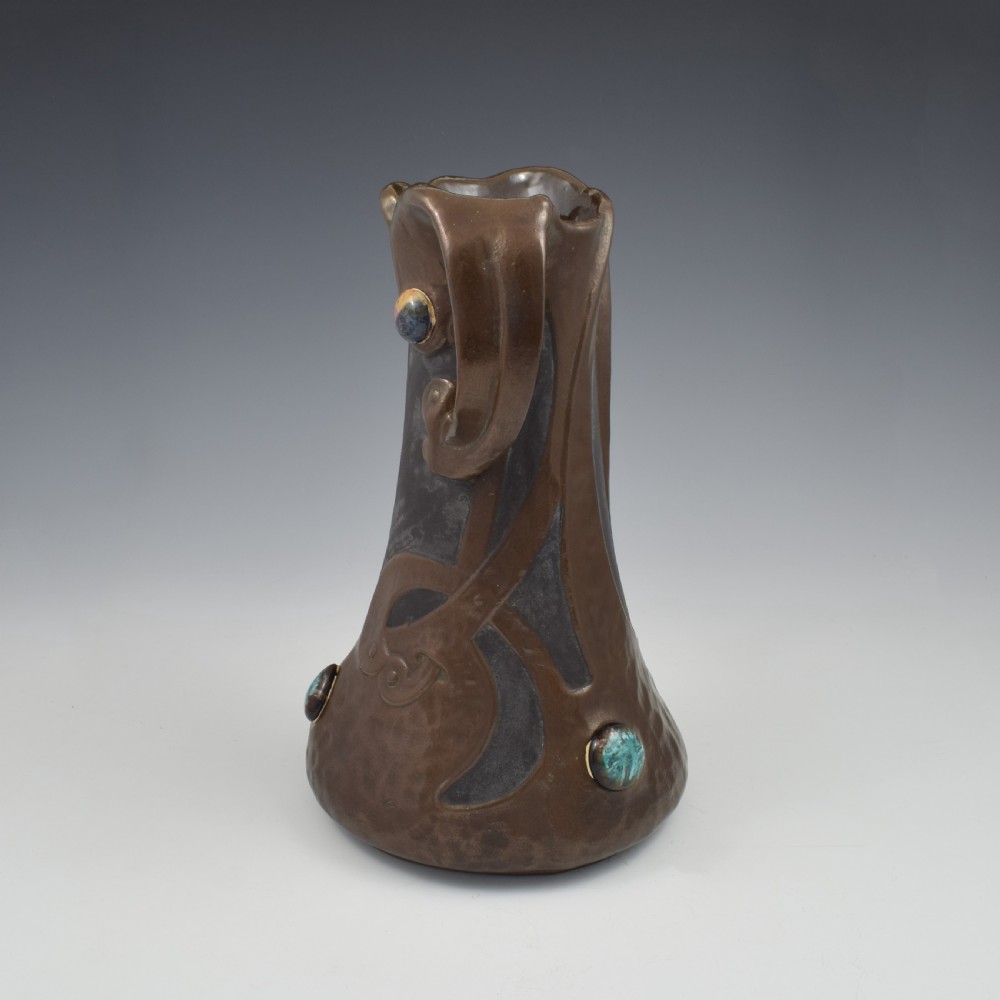 An Art Nouveau brown ceramic vase featuring a metallic copper effect surface, organic twin handles, flared rim, and inset colourful glazed cabochons. View VII