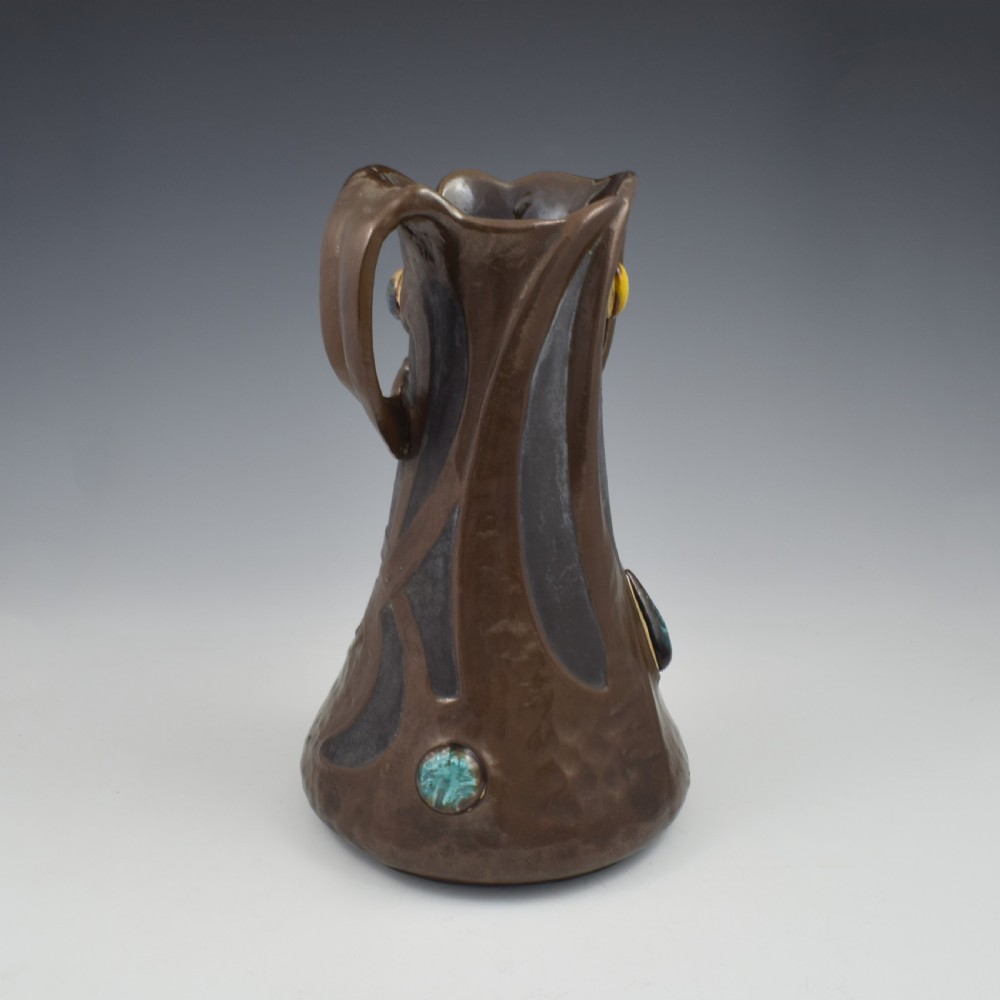 An Art Nouveau brown ceramic vase featuring a metallic copper effect surface, organic twin handles, flared rim, and inset colourful glazed cabochons. View VIII