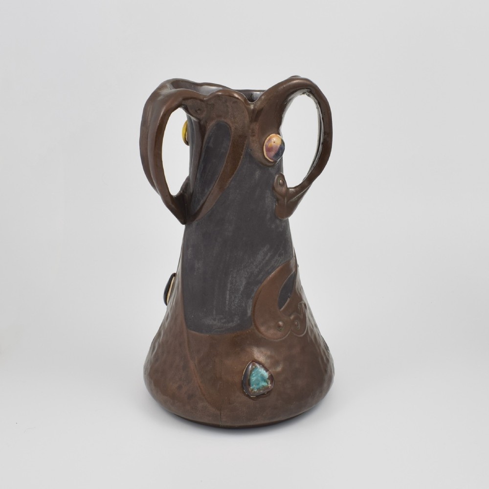 An Art Nouveau brown ceramic vase featuring a metallic copper effect surface, organic twin handles, flared rim, and inset colourful glazed cabochons. View XV