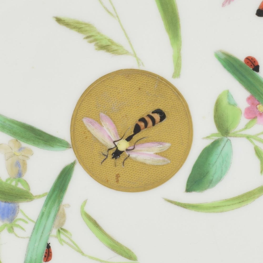 A white porcelain dessert plate decorated with hand-painted insects, green foliage, pink flowers, and a central gilt sun medallion with a gilded rim. View III
