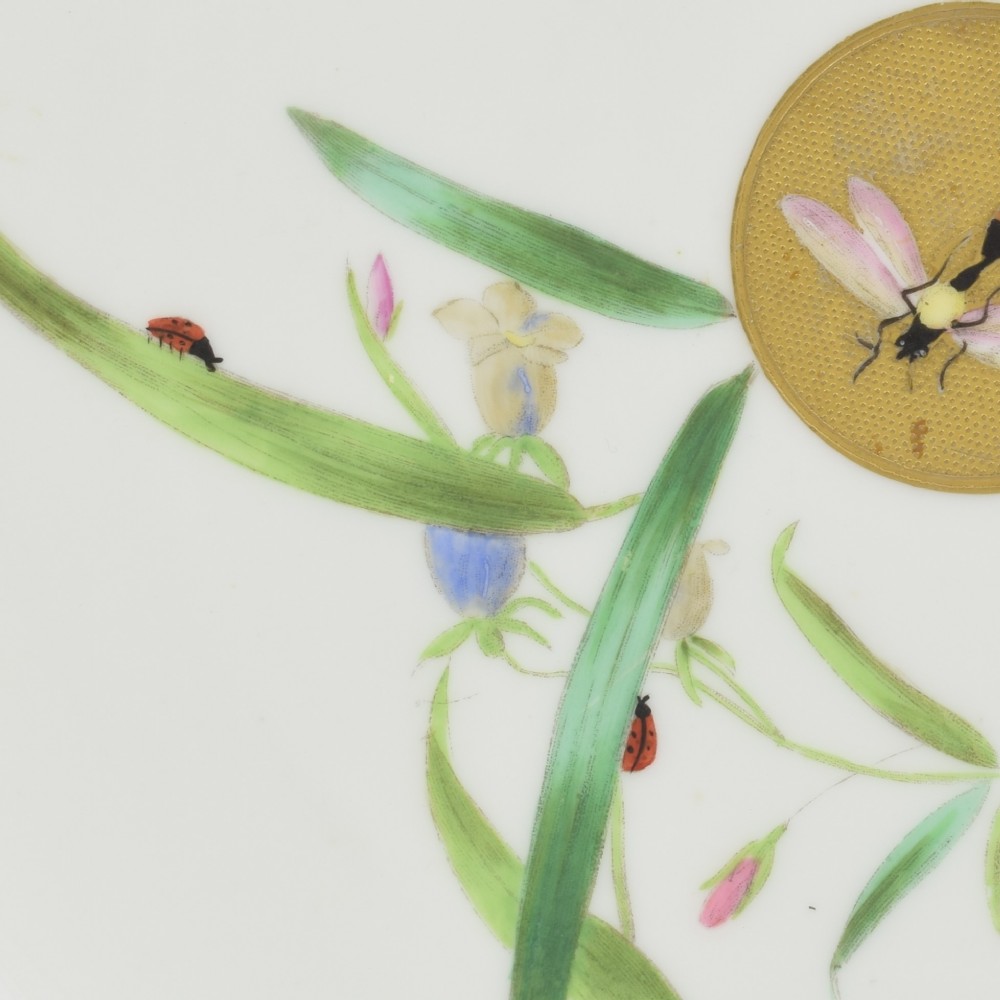 A white porcelain dessert plate decorated with hand-painted insects, green foliage, pink flowers, and a central gilt sun medallion with a gilded rim. View IV