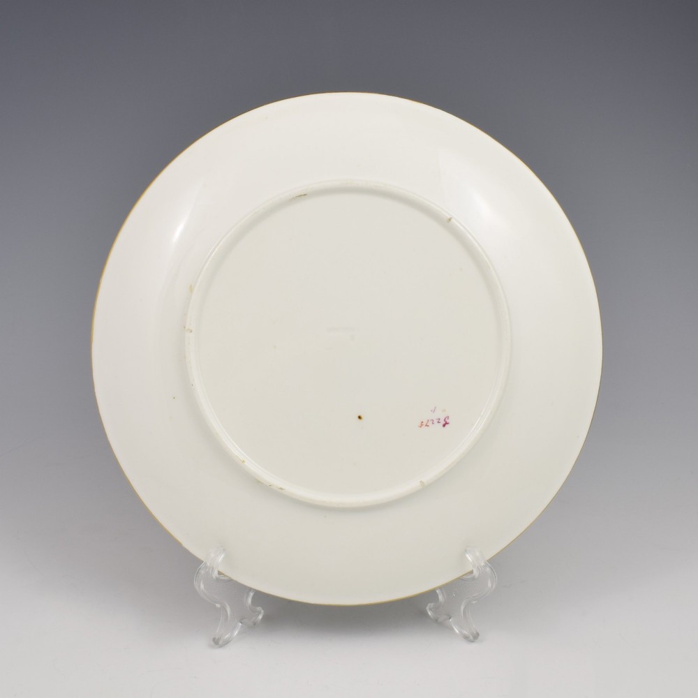 A white porcelain dessert plate decorated with hand-painted insects, green foliage, pink flowers, and a central gilt sun medallion with a gilded rim. View VI