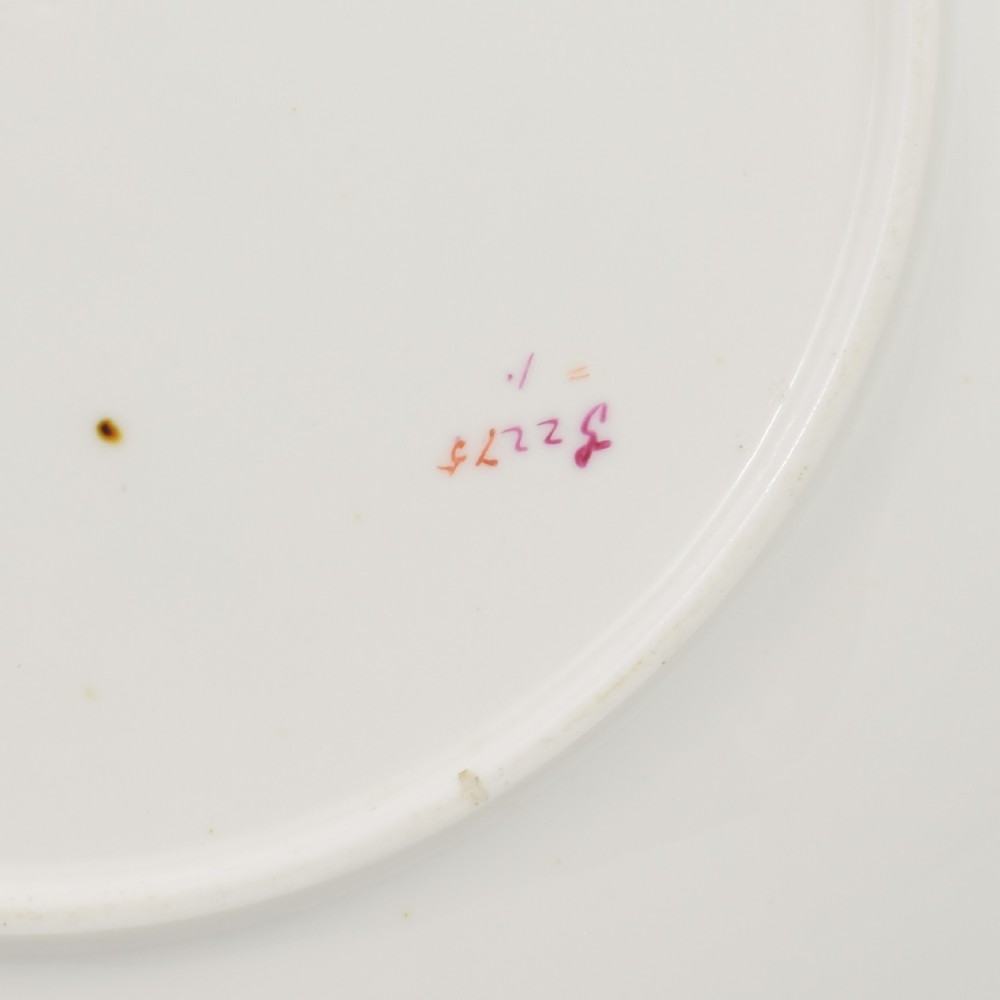 A white porcelain dessert plate decorated with hand-painted insects, green foliage, pink flowers, and a central gilt sun medallion with a gilded rim. View VII