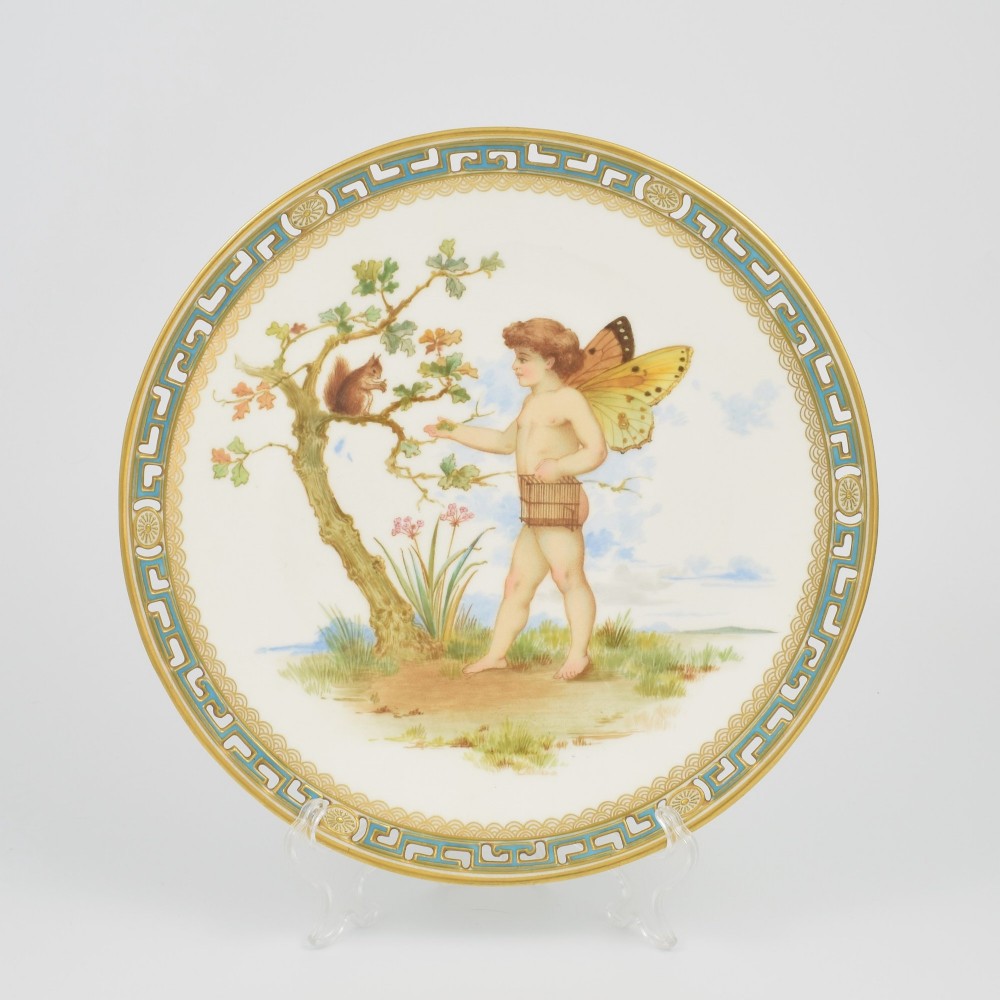 An antique round Minton porcelain cabinet plate featuring a reticulated gilt rim with turquoise trim and a hand-painted central illustration of a winged fairy near a squirrel in an oak tree.