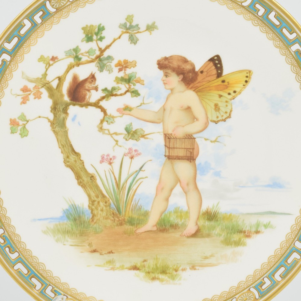 An antique round Minton porcelain cabinet plate featuring a reticulated gilt rim with turquoise trim and a hand-painted central illustration of a winged fairy near a squirrel in an oak tree. View II