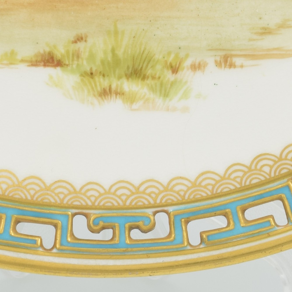 An antique round Minton porcelain cabinet plate featuring a reticulated gilt rim with turquoise trim and a hand-painted central illustration of a winged fairy near a squirrel in an oak tree. View VII