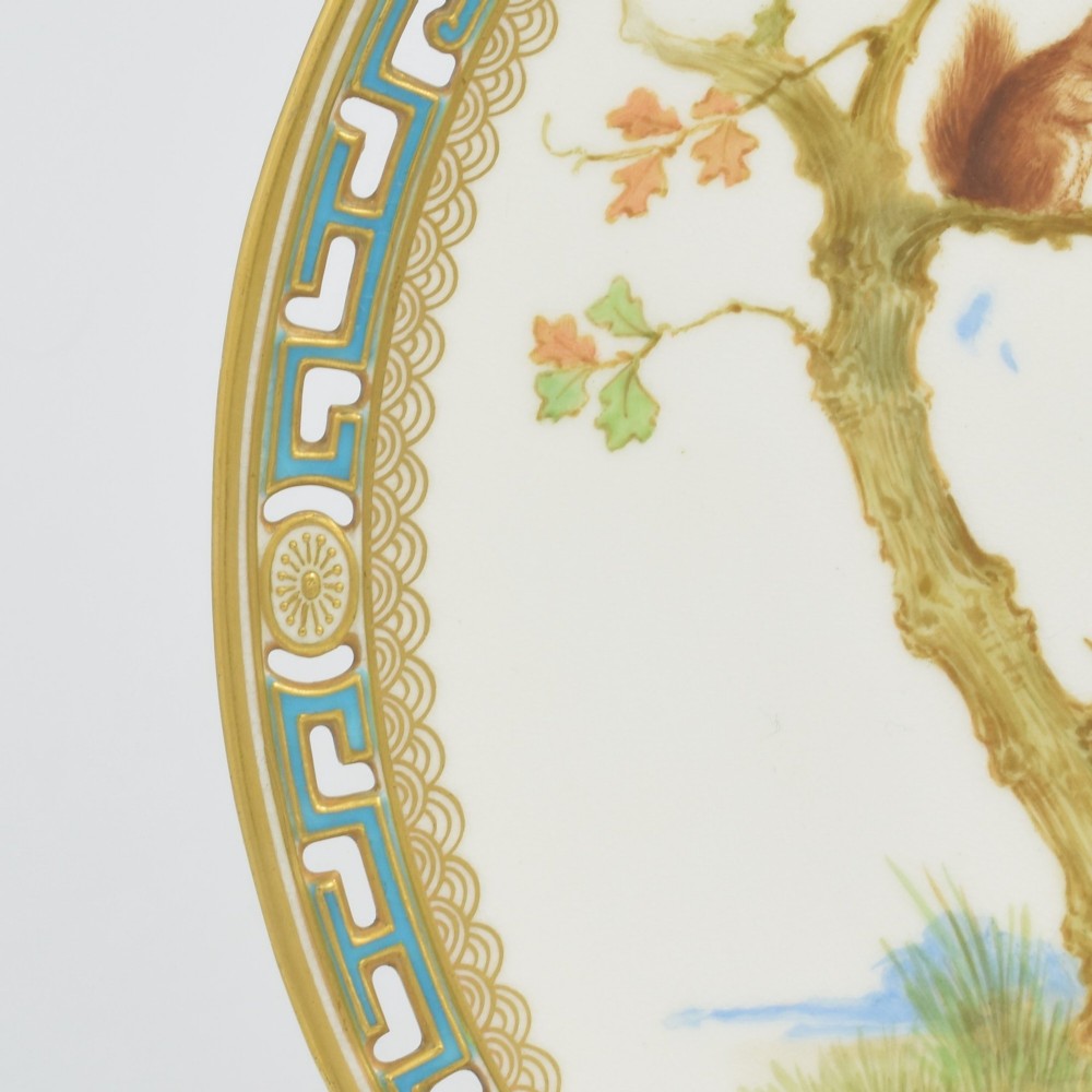 An antique round Minton porcelain cabinet plate featuring a reticulated gilt rim with turquoise trim and a hand-painted central illustration of a winged fairy near a squirrel in an oak tree. View VIII