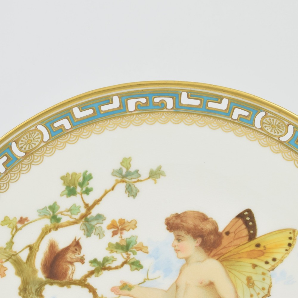 An antique round Minton porcelain cabinet plate featuring a reticulated gilt rim with turquoise trim and a hand-painted central illustration of a winged fairy near a squirrel in an oak tree. View IX