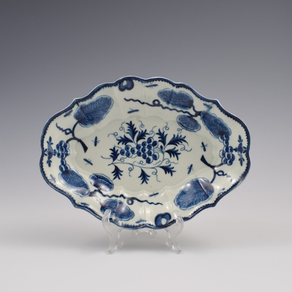 An oval 18th-century soft-paste porcelain dessert dish featuring a lobed rim decorated with underglaze cobalt blue foliage and botanical motifs on a white background.