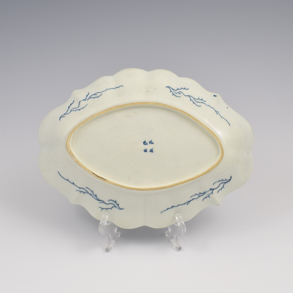An oval 18th-century soft-paste porcelain dessert dish featuring a lobed rim decorated with underglaze cobalt blue foliage and botanical motifs on a white background. View II
