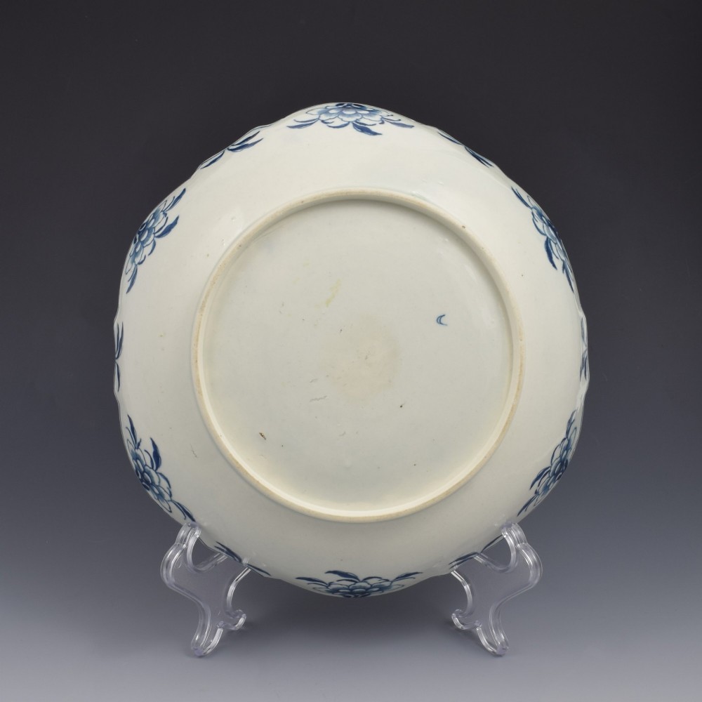 An eighteenth-century circular soft-paste porcelain junket dish featuring a scalloped rim, relief shell moulding, and painted blue floral motifs. View VI
