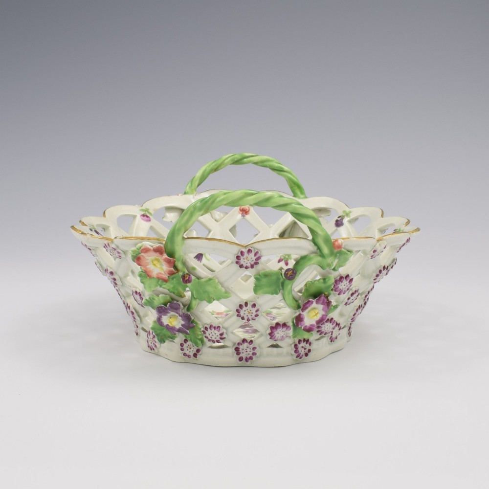 An eighteenth-century reticulated soft-paste porcelain chestnut basket featuring pierced lattice sides, green twig handles, and hand-painted polychrome floral decoration. View IV