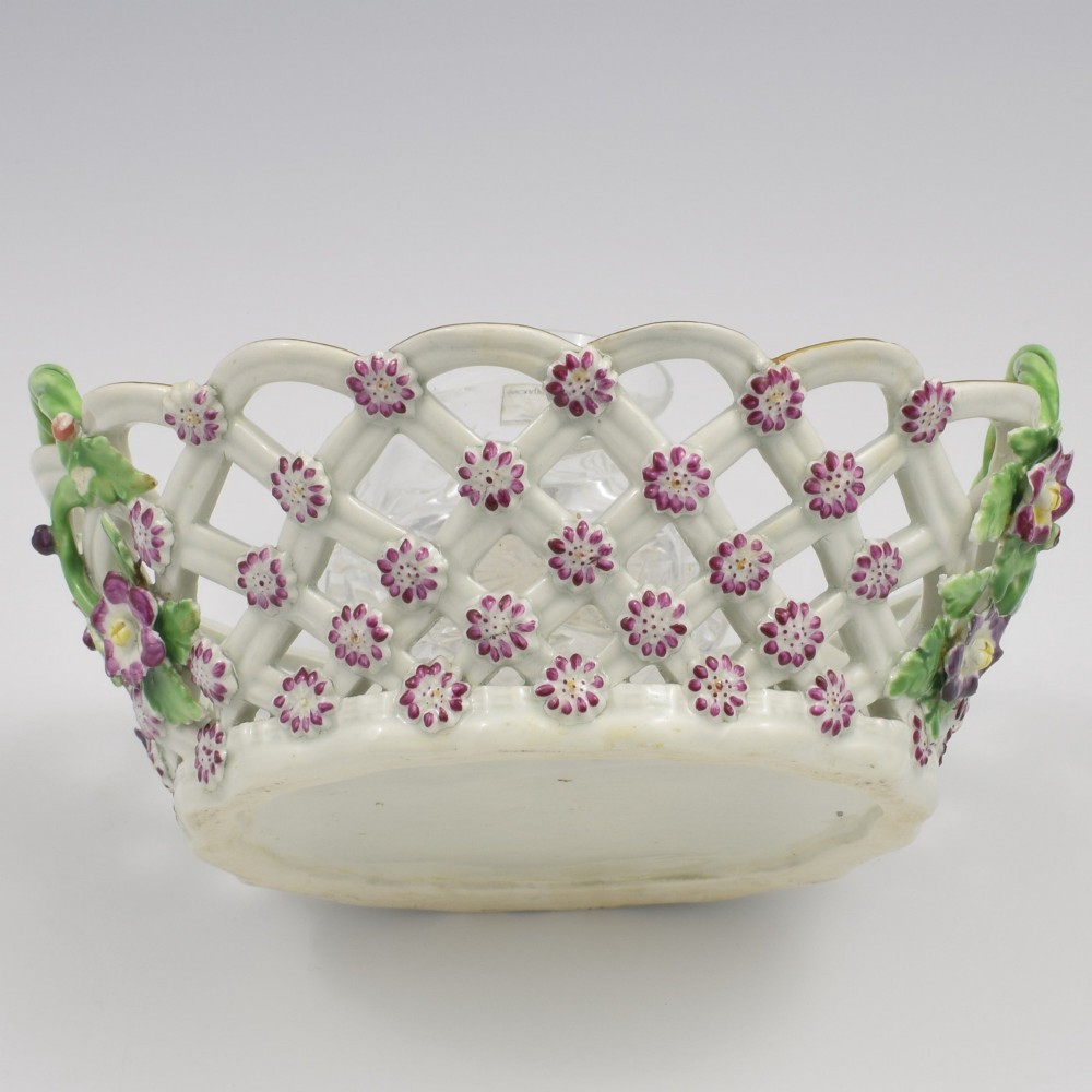 An eighteenth-century reticulated soft-paste porcelain chestnut basket featuring pierced lattice sides, green twig handles, and hand-painted polychrome floral decoration. View XI