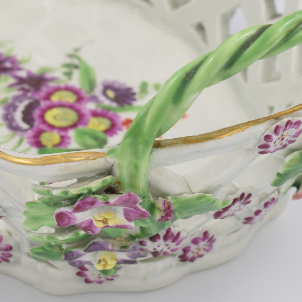 An eighteenth-century reticulated soft-paste porcelain chestnut basket featuring pierced lattice sides, green twig handles, and hand-painted polychrome floral decoration. View XII