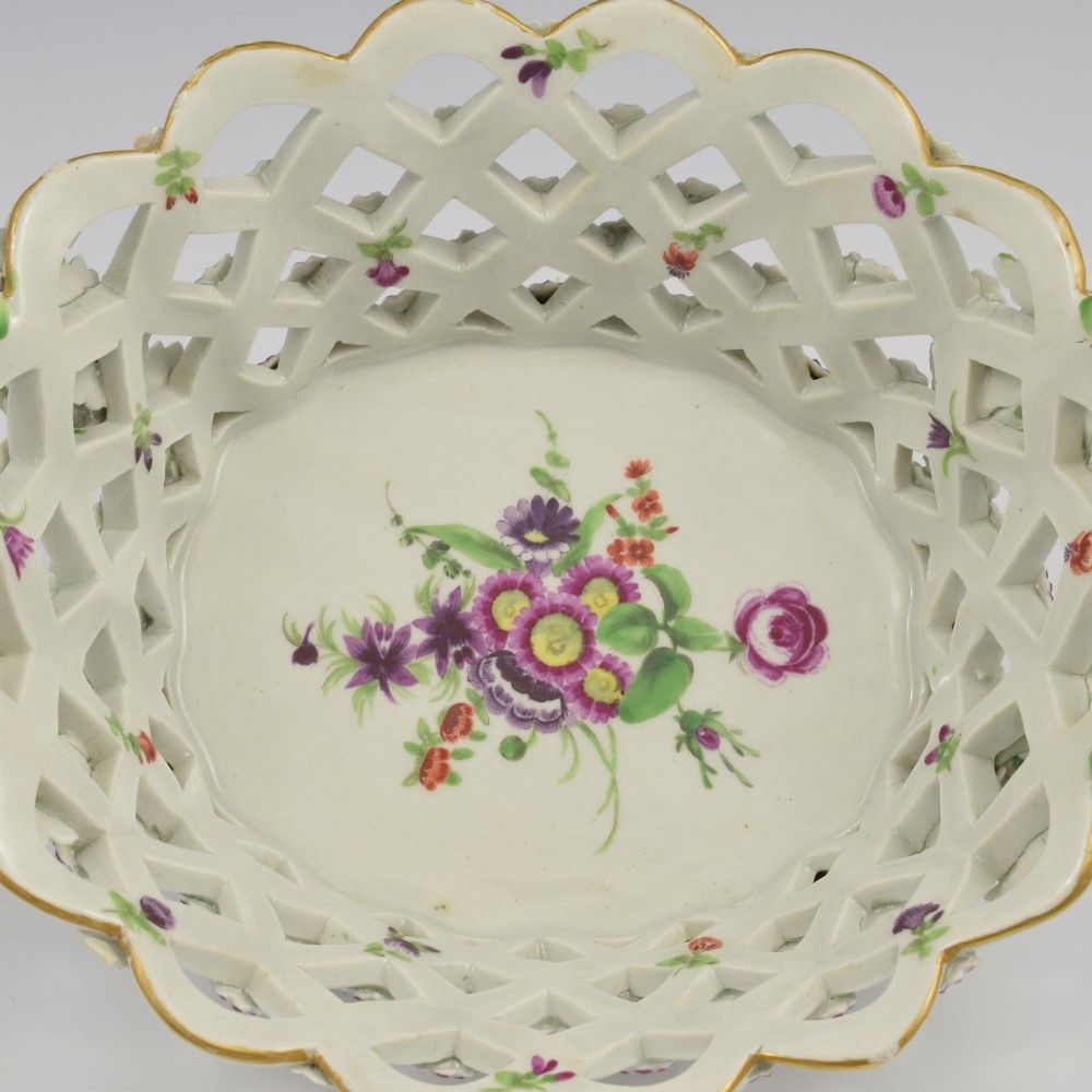 An eighteenth-century reticulated soft-paste porcelain chestnut basket featuring pierced lattice sides, green twig handles, and hand-painted polychrome floral decoration. View XIII