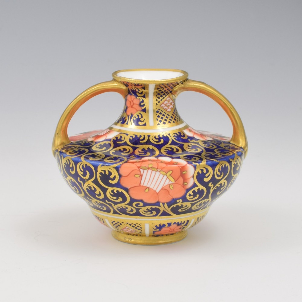 An Edwardian Royal Crown Derby miniature twin-handled porcelain vase decorated with an Imari floral pattern in cobalt blue, iron red, and gilt.
