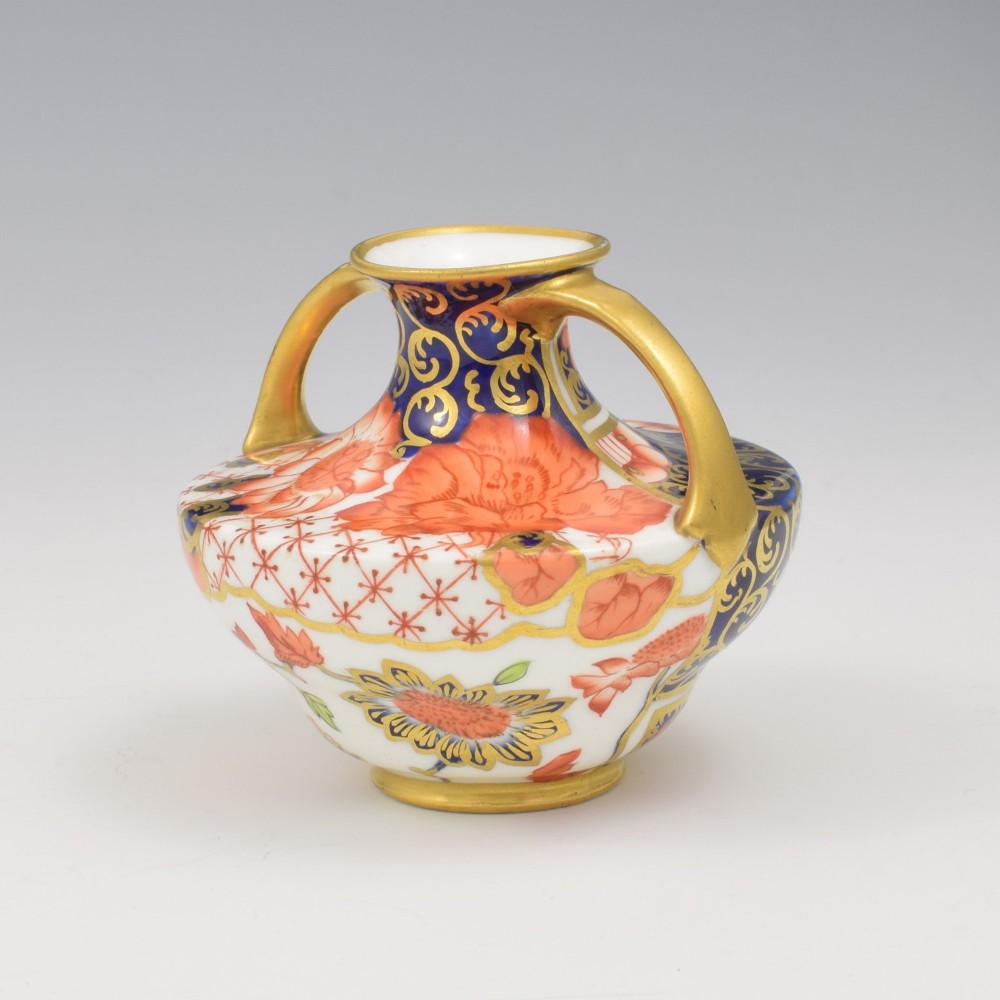 An Edwardian Royal Crown Derby miniature twin-handled porcelain vase decorated with an Imari floral pattern in cobalt blue, iron red, and gilt. View IV
