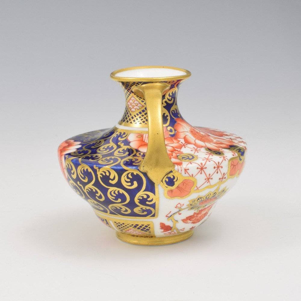An Edwardian Royal Crown Derby miniature twin-handled porcelain vase decorated with an Imari floral pattern in cobalt blue, iron red, and gilt. View VII