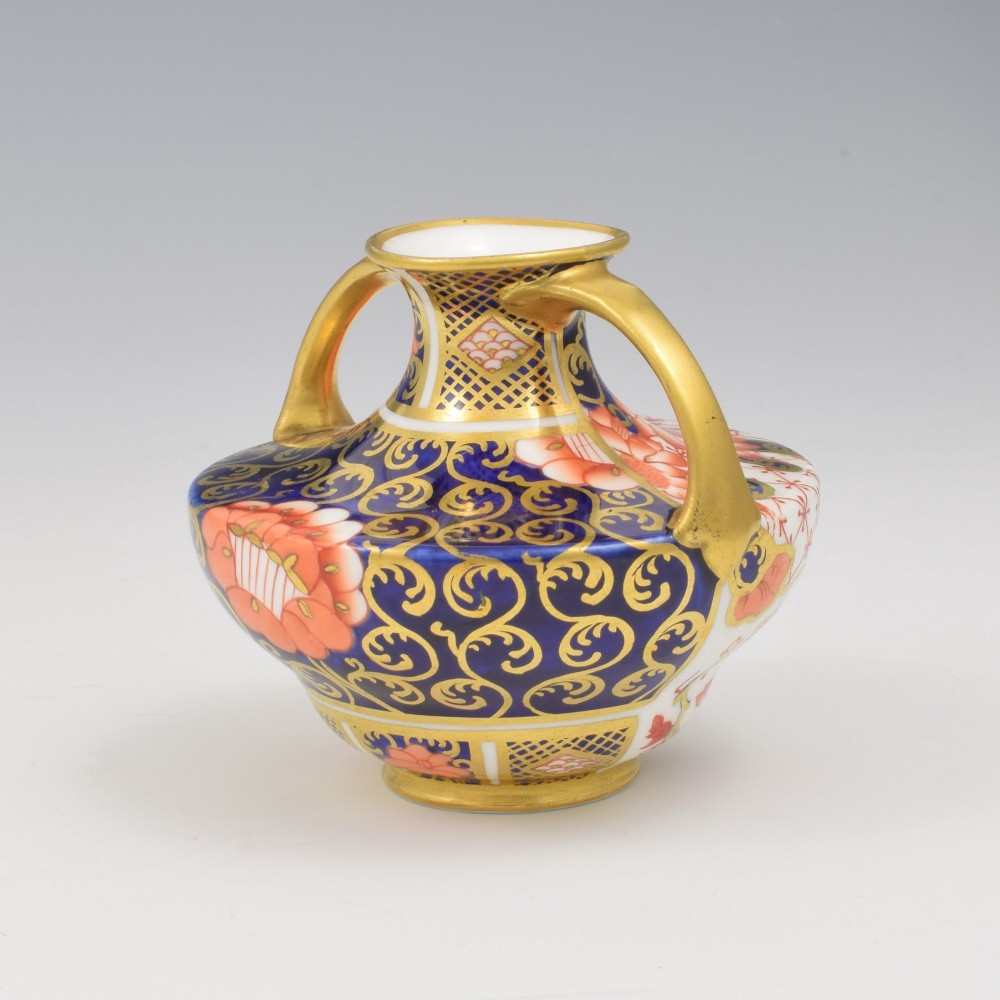 An Edwardian Royal Crown Derby miniature twin-handled porcelain vase decorated with an Imari floral pattern in cobalt blue, iron red, and gilt. View VIII